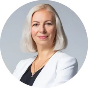 Professional headshot of a woman with shoulder-length silver hair wearing a white blazer against a light gray background.